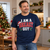 Lifestyle mockup of a model wearing the navy NEWTZ I Am A Breast Guy vintage Christmas T-shirt at a festive gathering