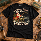Christmas Dinner Can Wait — I've Got a Bite fishing Christmas T-shirt — wooden workbench flat lay