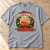 Have a Holly Dolly Christmas T-Shirt — Heather Grey flat lay on a wooden workbench