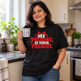 Illustrative lifestyle mockup of a woman wearing the black My Presence Is Your Present T-shirt in a kitchen