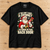 No Chimney Back Door Santa Christmas T-Shirt — Black flat lay on a wooden workbench