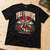 NEWTZ Yule Fighters Christmas T-shirt lying flat on a plywood studio workbench